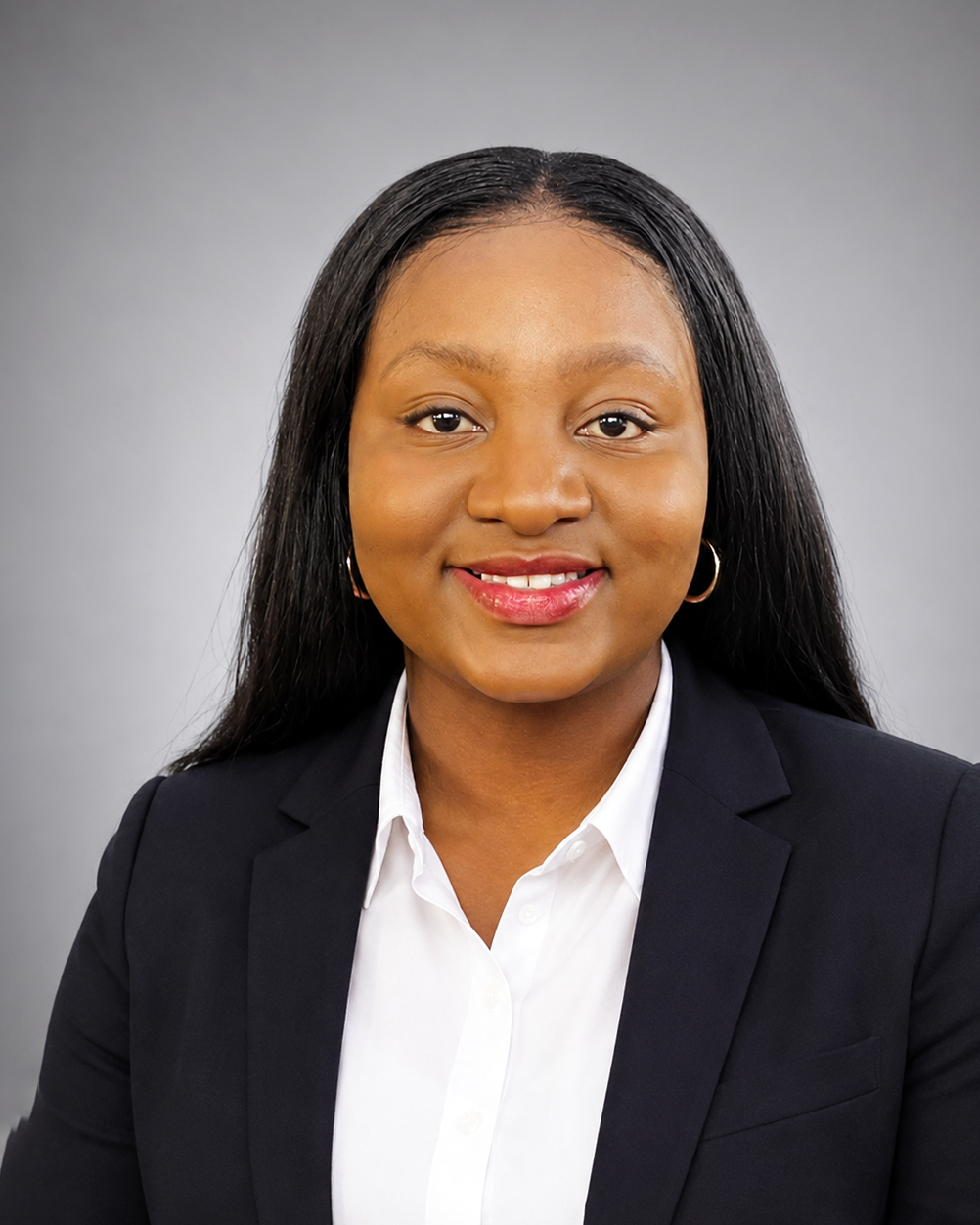 Professional headshot of a smiling woman in a navy blazer and white shirt against a gray studio background.